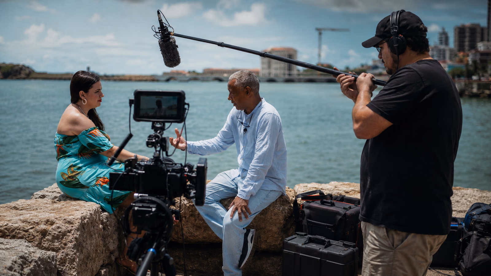 Equipe de produção audiovisual gravando ao ar livre com câmera e microfone boom.
