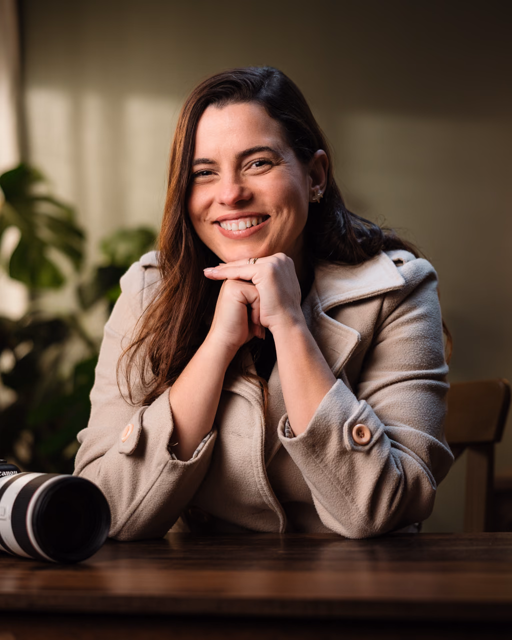 Retrato da Cris sorrindo em um estúdio, apoiada sobre as mãos, com uma câmera em primeiro plano.